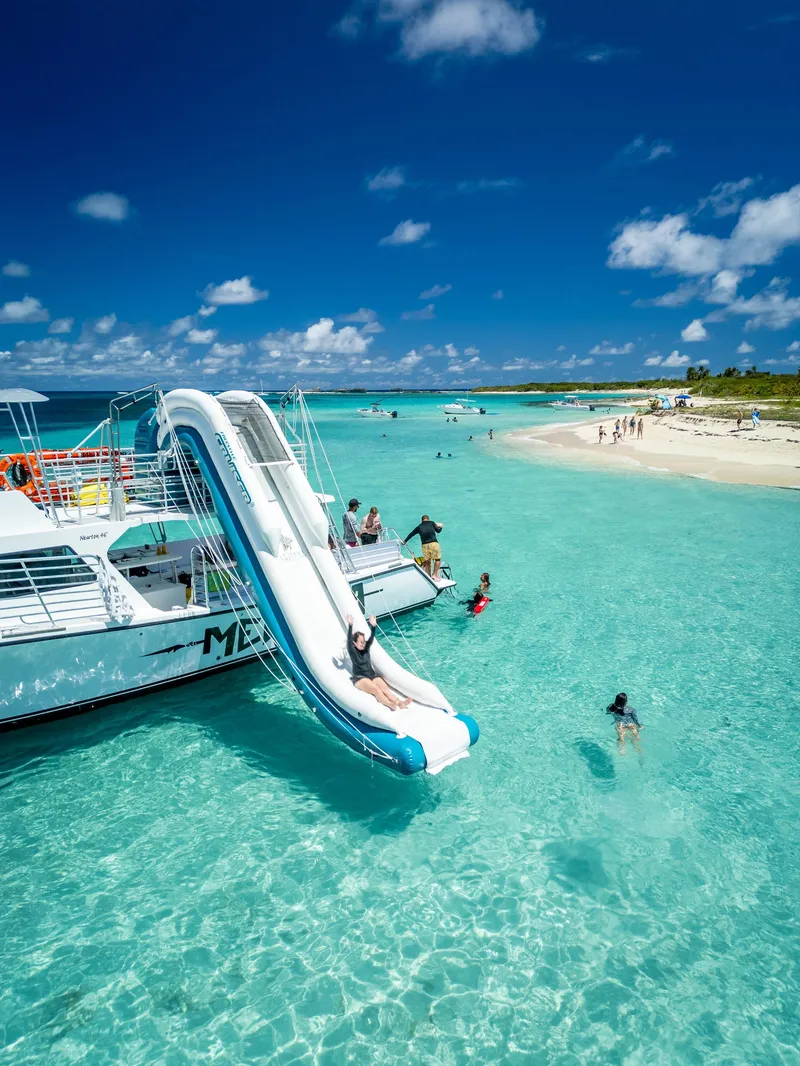 Tourists launching off a water slide into clear Caribbean water on an Icacos Island snorkeling cruise from Fajardo